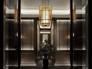 A well-lit hallway with a glass vase on a table and a metal chandelier hanging from the ceiling, surrounded by doors and decorated with flowers