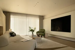 A modern living room with a flat screen TV, a couch, chair, coffee table, and decorative plant and vase, in a minimalist style with a focus on functionality and simplicity