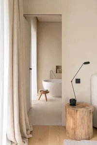 Bathroom with a white tub, sink, and toilet, set against a wooden floor and dimly lit for a cozy atmosphere
