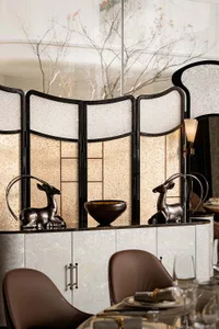 A well-lit dining room with a wooden table and chairs, surrounded by a large window allowing natural light to enter
