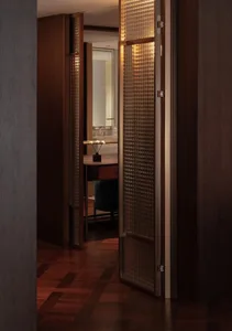 Bathroom with a wooden floor, sink, mirror, and open door, featuring dim lighting and a cozy atmosphere