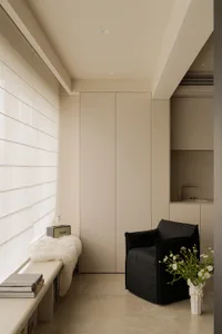 Comfortable living space with a black chair, couch, and dining table, well-lit with a vase of flowers on a table