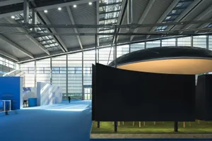 A modern art gallery with a black wall, glass dome, and various sculptures on display