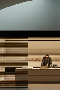 A dimly lit modern room with a wooden counter, a laptop, and a man working, creating a cozy atmosphere