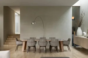 A modern dining room with a wooden table surrounded by chairs, set with a vase, and featuring a combination of wood and metal elements, with natural light creating a warm and inviting atmosphere