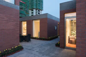 A modern living space with a brick exterior, large window, and a well-lit interior with a dining table and chairs