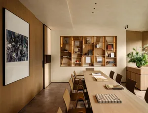 A well-used conference room with a wooden table and chairs, surrounded by books and magazines, creating a comfortable space for gatherings or meetings