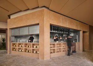 A busy restaurant kitchen with a brown color scheme, featuring a counter with bowls and cups, and two people working