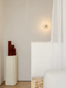 A minimalist bedroom with a white bed, white wall, and white curtain, with soft and diffused lighting creating a calm atmosphere