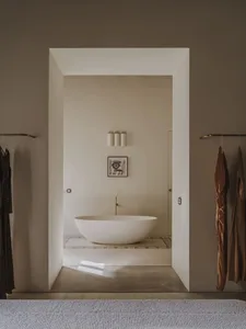 A well-lit bathroom with a white bathtub and doorway, surrounded by a predominantly white space with a calm and relaxing atmosphere