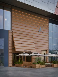 A restaurant patio with wooden exterior, umbrellas, chairs, and dining tables, well-lit with natural light