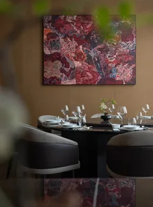 A formal dining room with a modern table setting, surrounded by chairs, a potted plant, and well-lit for a warm atmosphere