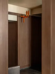 Warm and intimate bathroom with wooden walls, a wooden door, and a wooden cabinet in a brown color scheme, with dim lighting