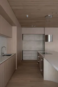 Warm and elegant kitchen with wooden cabinets, marble countertop, sink, oven, and refrigerator, dim lighting creating a cozy atmosphere