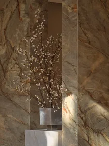 A modern room with a stone wall, a metal vase with white flowers, and soft, diffused lighting