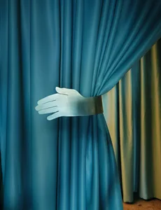 A blue curtain with a white-gloved hand waving from behind it, creating a mysterious and intriguing scene
