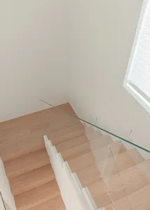 A modern staircase with a glass railing in a bright and airy white room with natural light