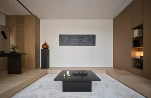 A minimalist living room with a black coffee table, white walls, and a couch and chair, set against a simple background