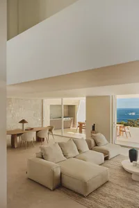 Photographed modern living room with a white couch, brown dining table, and kitchen area, well-lit and inviting