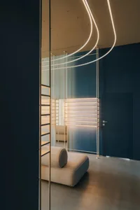 A modern living room with a blue wall, white couch, and a staircase leading to a loft area with soft diffused lighting