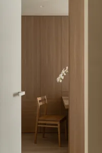 Dining room with wooden walls and table, a wooden chair, and a vase with flowers adding a touch of elegance