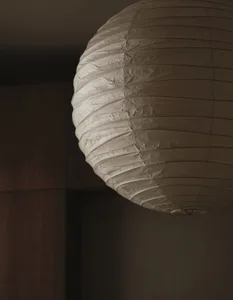 A dimly lit room with a unique paper lamp hanging from the ceiling, the focus is on the lamp