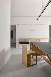 A dimly lit kitchen with a wooden counter and two chairs, featuring a minimalist design