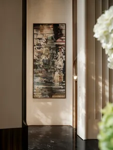 A modern room with a large black and white painting on the wall, surrounded by a white color scheme and subtle shadows