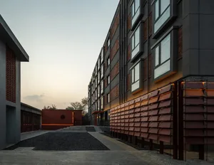 A large building with a brick facade and numerous windows, set against a soft and diffused background, creating a warm and inviting atmosphere