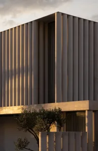 A modern building with a tan exterior, concrete construction, and a large window, set against a warm and inviting natural light background