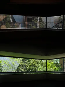 A serene photograph of a modern building with a large window and a view of the surrounding forest