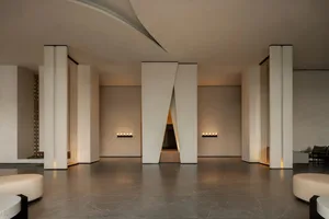 A large, empty, modern room with a curved white wall, natural light, and clean lines