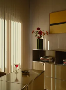 Cozy living room with a yellow color scheme, wooden furniture, and dim lighting, featuring a dining table, chair, vase, martini glass, bowl, and book