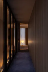Narrow hallway with wooden floor and walls, dim lighting, and a bed on the left, creating a cozy and intimate atmosphere