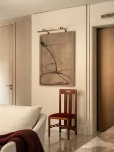 Comfortable living space with a white couch, brown chair, and a painting on the wall, surrounded by neutral colors and well-lit