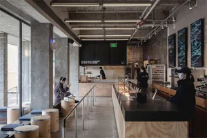 Bright and modern restaurant with concrete, wood, and metal features, filled with people enjoying a lively atmosphere