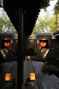 A serene traditional Chinese courtyard with a stone exterior, illuminated by natural light and featuring a fountain