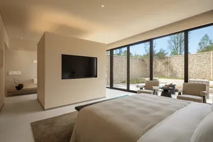 Bright and inviting living room with a modern style, white walls, a large flat screen TV, a bed, a chair, and a dining table, with natural light coming in through the windows