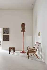 Cozy living space with a white wall, a red pole, a brown chair, and a dining table with wooden chairs, well-lit by natural light from a window