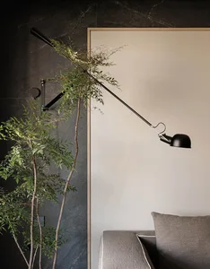 Cozy living space with a floor lamp casting warm light on the wall and surrounding area, featuring a couch and a potted plant