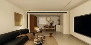 Cozy living room with wooden furniture, a rug, and a well-lit atmosphere, visible kitchen in the background