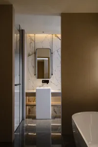 Bathroom with a white bathtub, toilet, marble countertop, and sink, set against a brown wall with dim lighting