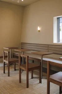 Cozy dining space with a wooden floor, white walls, and natural light from a window, featuring a bench and chairs around a dining table