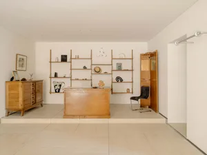 Cozy home office with a wooden desk, a chair, and a large bookshelf filled with books, creating a warm and inviting atmosphere
