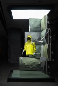 一個穿著黃雨衣的人偶站在一間店或展示區的燦爛的綠色背景前