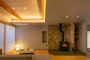 Cozy living room with a stone fireplace, stone walls, a couch, coffee table, and chair, creating a warm and inviting space for relaxation and socializing