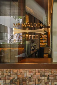 A cozy coffee shop with a brown color scheme, featuring a window display with a coffee cup and a variety of books, creating an inviting atmosphere