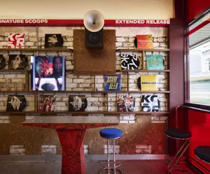 A warm and inviting restaurant with a red table and wall, featuring a book display and a cozy atmosphere