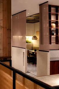 A warm and inviting dining area with a wooden table, chairs, and potted plants, surrounded by a well-lit kitchen with a sink and oven