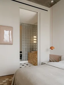 A modern bedroom with a white color scheme, a tile floor, and a bed, mirror, and lamp, with a window and a minimalist style